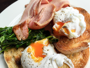 How long to poach an egg in boiling water? Poached Eggs on a plate with Bacon, Spinach and Toast.