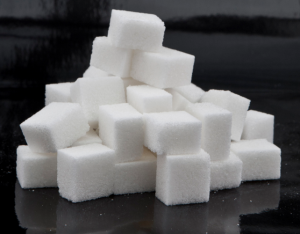 How Many Grams Of Sugar Should You Have A Day? A group of sugar cubes on a black table top.