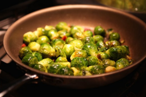 Brussel Sprout Recipe with Bacon a brown pan cooking brussel sprouts and bacon.