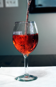 How Many Calories in a Bottle of Red Wine, a wine glass on a white table being filled with Red Wine.