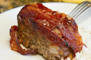 How Long To Bake Meatloaf At 375, a slice of meatloaf on a white plate.