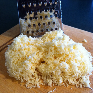fontina cheese substitute, grated cheese on a wooden table top.